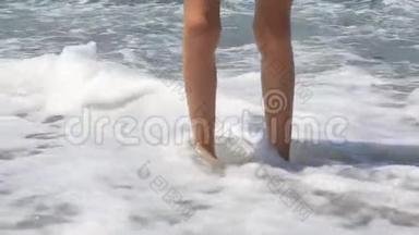 男孩`脚在海里，一个十几岁的少年站在海滩上的鹅卵石海滩上。 自然假期。